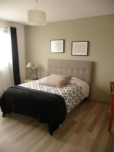 una camera da letto con un letto con un piumone bianco e nero di Chambres d'hôtes dans maison contemporaine a Vernouillet