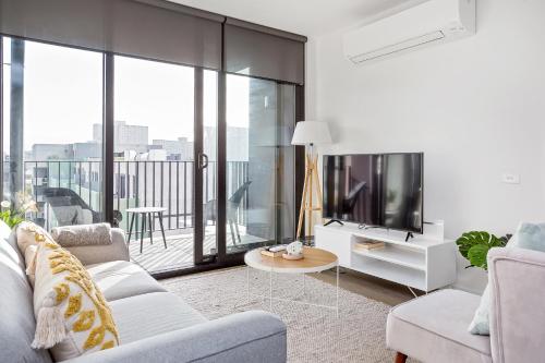 a living room with a couch and a tv at Palmerston St Apartments by Urban Rest in Melbourne