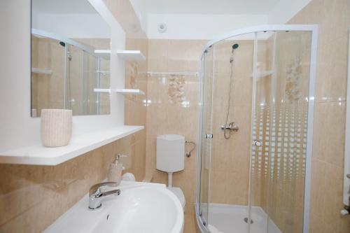 La salle de bains est pourvue d'un lavabo et d'une douche en verre. dans l'établissement Pensiunea Casa Marica, à Băile Herculane