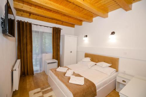 - une chambre avec un lit et une télévision dans l'établissement Pensiunea Casa Marica, à Băile Herculane