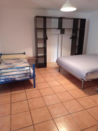 een slaapkamer met 2 bedden en een tegelvloer bij Plein pied dans maison de caractère in Montjaux