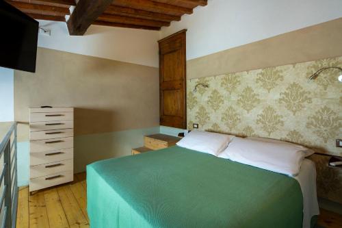 a bedroom with a green bed and a dresser at Hotel Le Capanne in Arezzo