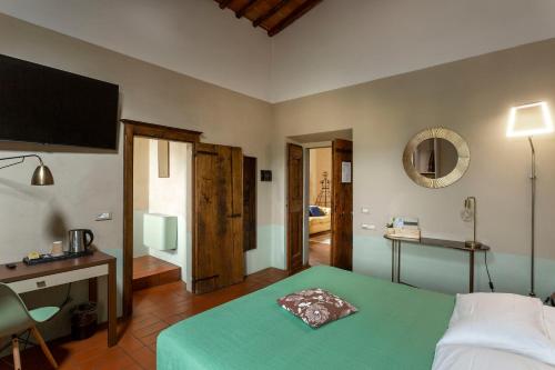 a bedroom with a green bed with a desk and a mirror at Hotel Le Capanne in Arezzo