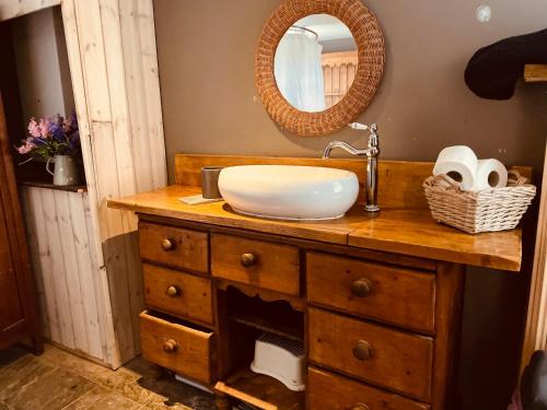 baño con lavabo y tocador con espejo. en Alfie Acres - Secluded Cabin set in 5 Acres of Privacy, with Exclusive use of Swimming Pool and Hot Tub for up to 10 Guests, en Downham