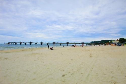 a group of people on a beach with a pier at Prima Playa in Międzyzdroje