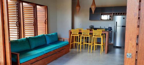 a kitchen with a blue couch and yellow stools at Cond ReservaTaipu, apart 202 in Barra Grande