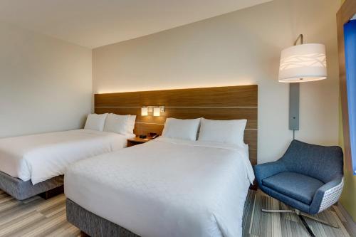 a hotel room with two beds and a chair at Holiday Inn Express - Wilmington - Porters Neck by IHG in Wilmington