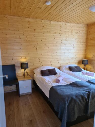 two beds in a room with wooden walls at Starmýri 2 Cottages in Starmýri