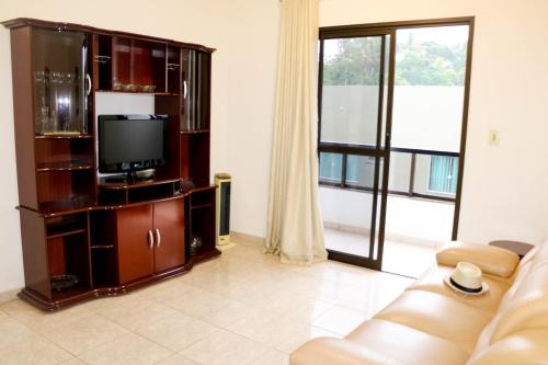 sala de estar con TV y sofá en Ótimo apartamento na Praia dos Castelhanos com Wi-Fi, en Anchieta