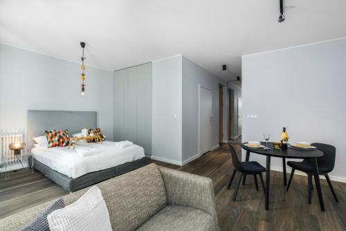 sypialnia z łóżkiem, stołem i kanapą w obiekcie Maraton Gardens Apartments by Renters w Poznaniu