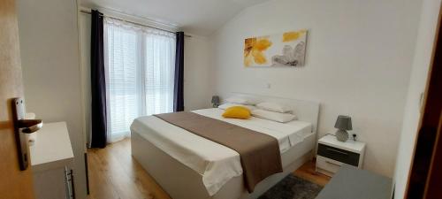 a bedroom with a bed with a yellow pillow on it at Apartments Marijana in Rab