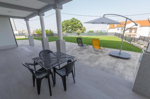 a patio with a table and chairs and an umbrella at Apartments Luka in Senj