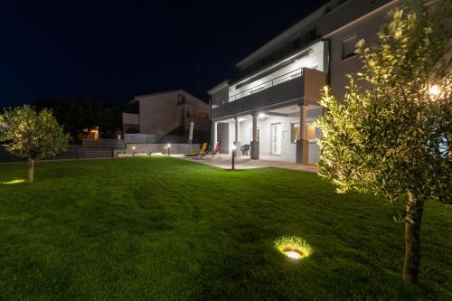 a house with a green yard at night at Apartments Luka in Senj