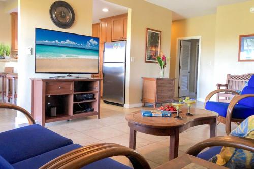 a living room with a television and a table at Poipu Sands 214 in Kipu