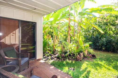 a screened in porch with chairs and a garden at Waikomo Streams 202 in Kipu