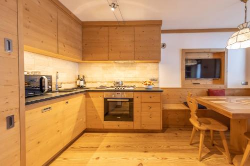 Una cocina con gabinetes de madera y una mesa de madera. en Cadin Apartment, en Cortina dʼAmpezzo