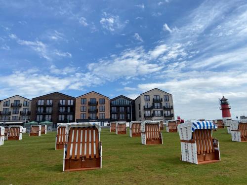 a row of lawn chairs sitting in a field with a lighthouse at Capt'n Eike in Westerdeichstrich