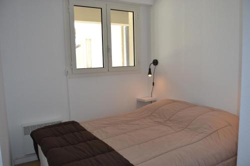 ein Schlafzimmer mit einem Bett und einem Fenster in der Unterkunft Appartement Wimereux "les pieds dans l'eau", parking, wifi in Wimereux