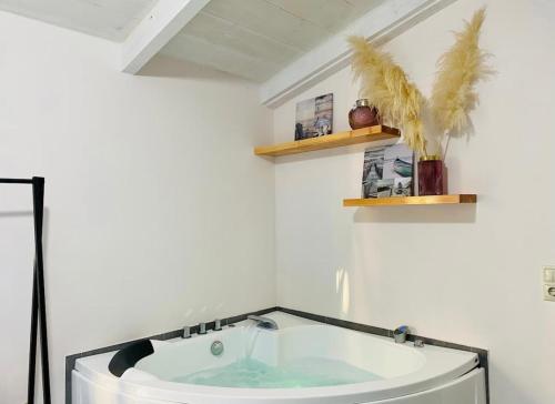 a bath tub in a white room with shelves at Green room in Marathopolis