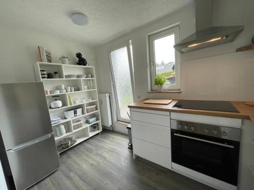 La cuisine est équipée de placards blancs et d'un four avec plaques de cuisson. dans l'établissement Ferienwohnung Katzenberg, à Bad Soden-Salmünster