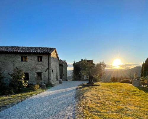 an old stone building with the sun setting in the background at Country House Ca' di Nieri - The Saints' Lodge in Monte Santa Maria Tiberina