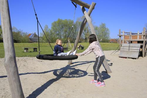 two young girls playing on a playground at Jacuzzi & Sauna Villa 2 in Tzummarum