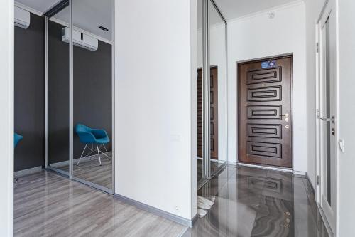 a hallway with mirrors and a door with a blue chair at Odesa Pearl Apartments in Odesa