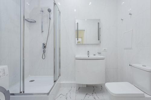 a white bathroom with a shower and a toilet and a sink at Odesa Pearl Apartments in Odesa