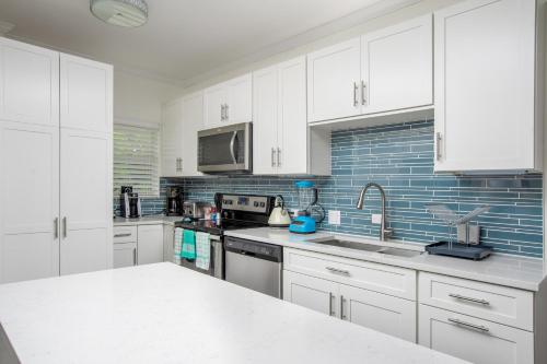 a white kitchen with white cabinets and a sink at Beach Living at Plantation Village BLGS in George Town