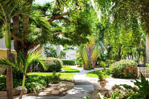 a garden with palm trees and a walkway at Beach Living at Plantation Village BLGS in George Town