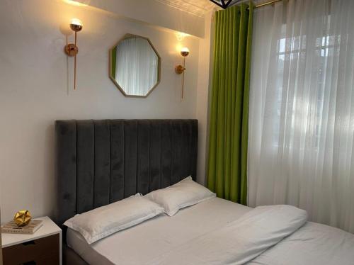 a bedroom with a bed with green curtains and a mirror at Sandalwood Suites Nakuru - Studios & One Bedroom Suites in Nakuru