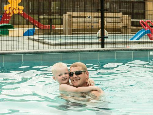a man and a baby in a swimming pool at Jacuzzi & Sauna Villa 2 in Tzummarum