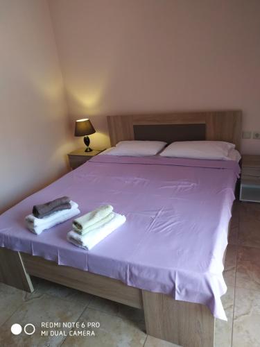 una camera da letto con un letto viola e asciugamani di La betia a Litóchoron