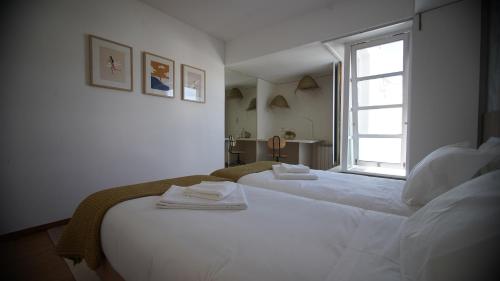 a white bedroom with two beds and a window at Sea Soul Esposende in Esposende