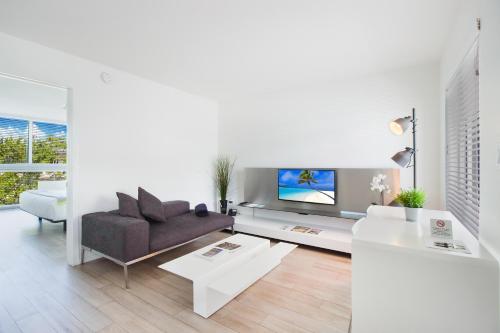 a white living room with a couch and a tv at Beach Haus Key Biscayne Contemporary Apartments in Miami