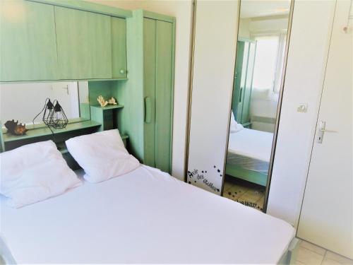 una camera da letto con un letto bianco e uno specchio di Appartement Port Fréjus avec Loggia et accès Plages à pieds a Fréjus