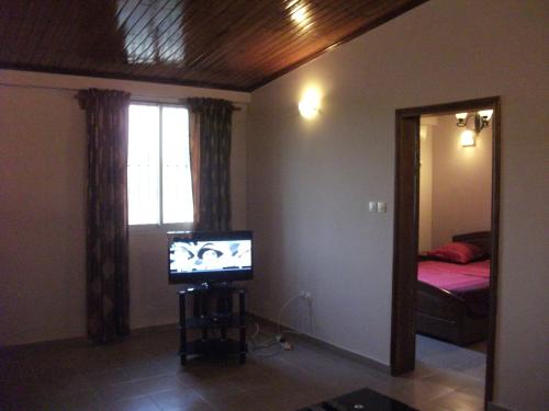 a living room with a television and a bedroom at Residence Japoma in Douala