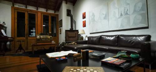 a living room with a black leather couch and a table at La Casa de los Limoneros in Colonia del Sacramento