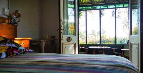 a bedroom with a bed and some windows and a table at La Casa de los Limoneros in Colonia del Sacramento