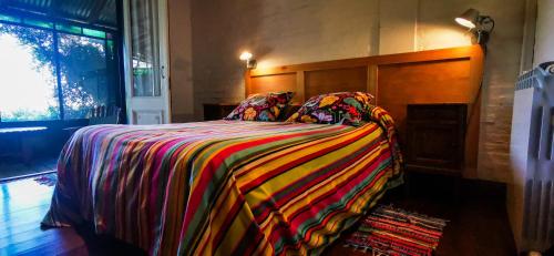 ein Schlafzimmer mit einem Bett mit einer bunten Decke in der Unterkunft La Casa de los Limoneros in Colonia del Sacramento