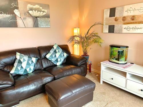 a brown leather couch in a living room with a fish tank at Sea View in Ardrossan