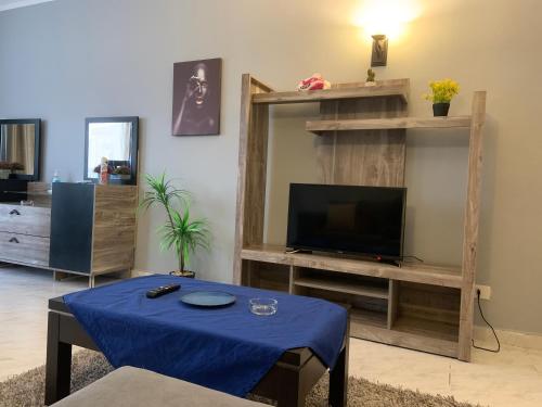 a living room with a tv and a blue table at Executive 2 BedRoom Hotel Apmt Contactless check-in Premium Services and Quality at Madinaty in Madīnat ash Shurūq