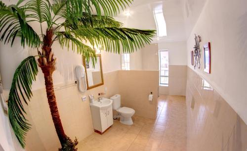 a bathroom with a toilet and a palm tree in it at Mayak Resort in Kam”yani Potoky