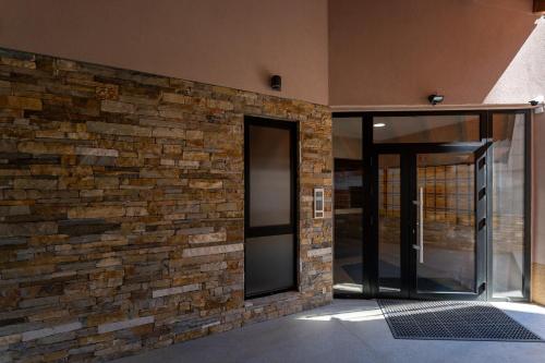 a brick wall with a glass door in a building at Apartman CROWN Zlatibor Vila Leonardo 6 in Zlatibor