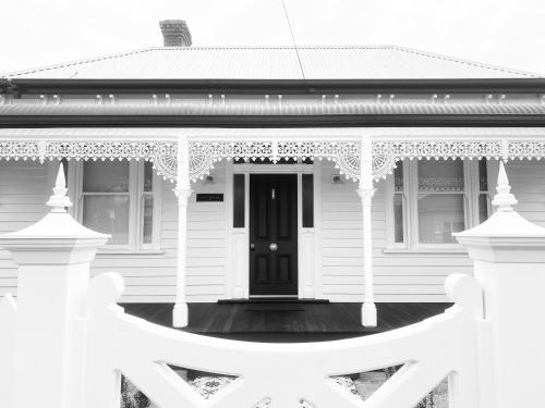 a white house with a black door and a porch at Castlebar - Superior Boutique Accomodation - Steps to Pakington Street in Geelong West