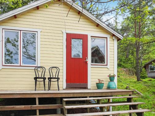 uma casa com uma porta vermelha e duas cadeiras num alpendre em 2 person holiday home in HANINGE em Haninge