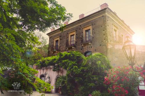 an old stone building with flowers in front of it at La Rocca della Rosa in Zafferana Etnea