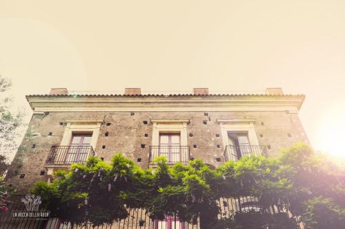 a tall brick building with windows and trees in front of it at La Rocca della Rosa in Zafferana Etnea