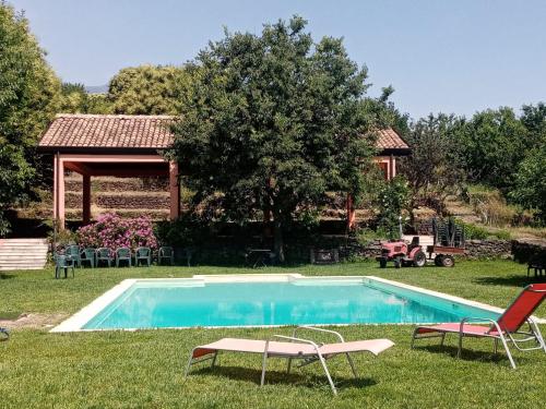 een zwembad met 2 ligstoelen en een paviljoen bij la Rocca delle Rose in Zafferana Etnea