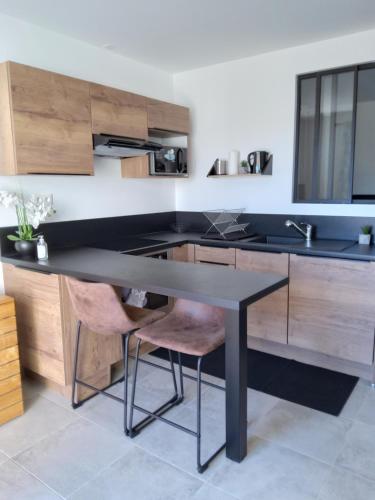 een keuken met een zwarte tafel en 2 stoelen bij Romytt Suite in Saint-Quentin-la-Poterie